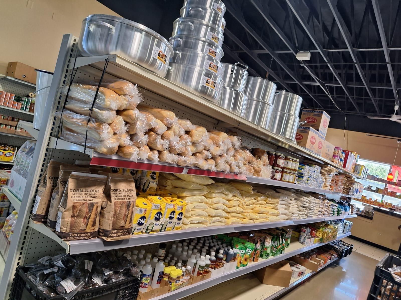 Bread, corn flour, and cassava flour on the shelves at JNS Food Market, with aluminum stock pots lined up on the rack above.