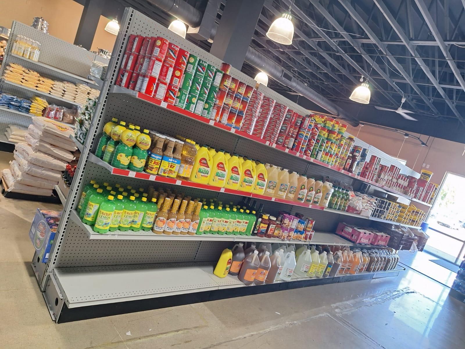 Cooking oil, lemon juice, canned goods, and household cleaners lining a long aisle at JNS Food Market.